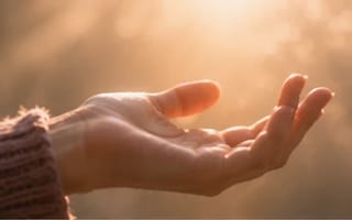 Mão se abrindo lentamente de um punho fechado em direção à luz quente — o alívio de soltar o ritual